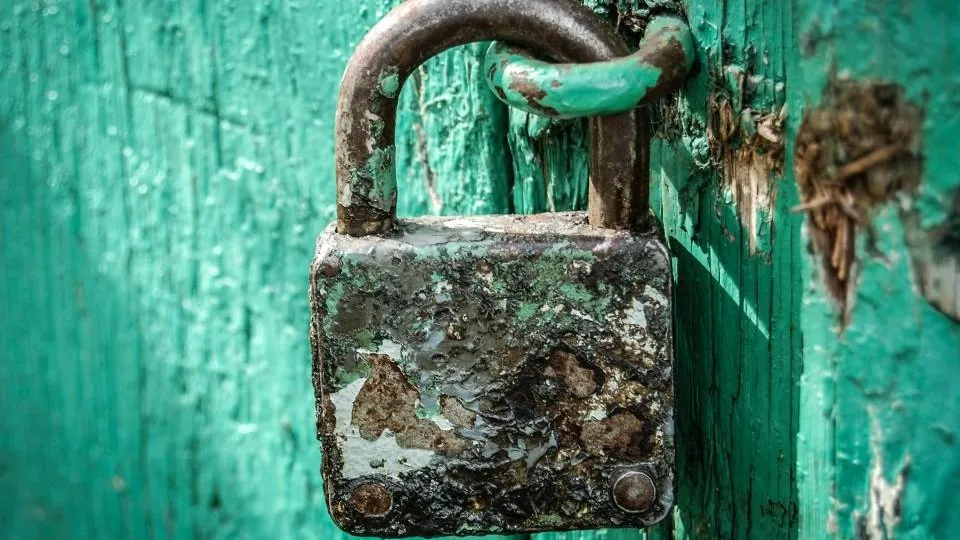 An old padlock securing a green wooden door